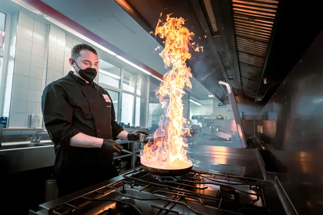 Koch flambiert in der Hotelküche des The Monarch Hotel – Hotelfotografie
